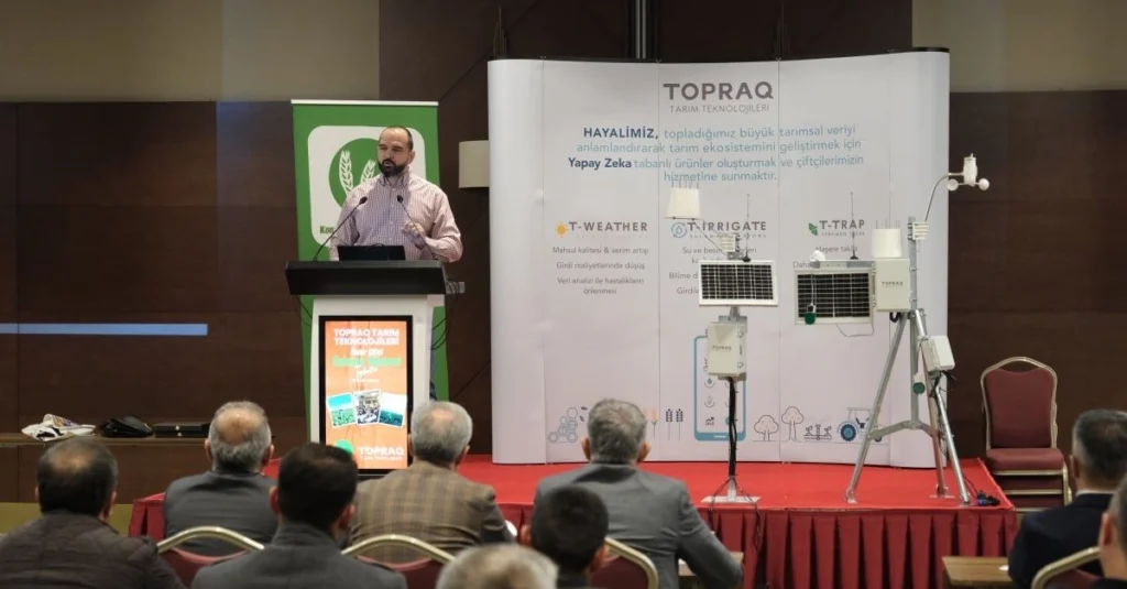 Topraq representative presenting agritech solutions, including T-Weather, T-Irrigate, and T-Trap, at a conference with an audience.
