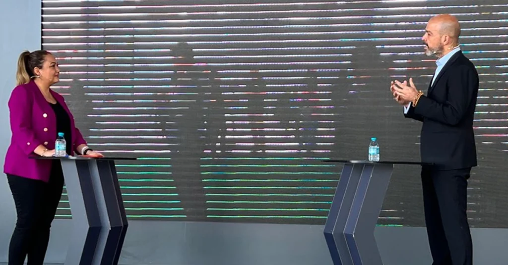 Image from an interview featuring two individuals on stage.